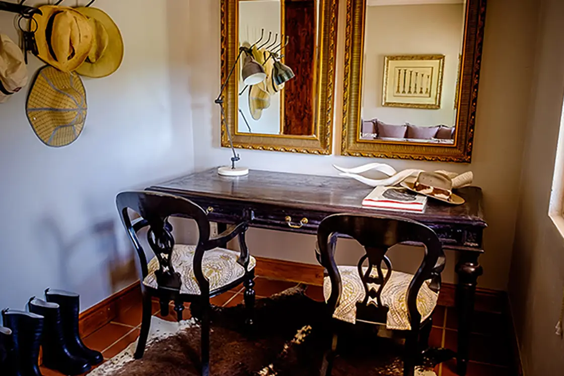 Perfect Hideaways property for sale: An antique, dark-wood vanity table below two gold-trim mirrors, featured in the entrance hall of a homestead in the Karoo. Olive Farm in Prince Albert.