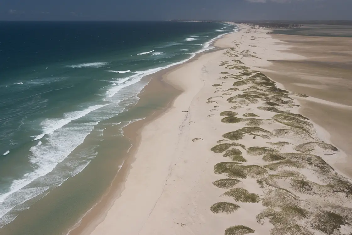 Perfect Hideaways real estate property: A stretch of coastline extends toward the horizon with the ocean on the left-hand side, and an intertidal coastal area on the right. The Sanctuary Private Reserve, Mozambique.