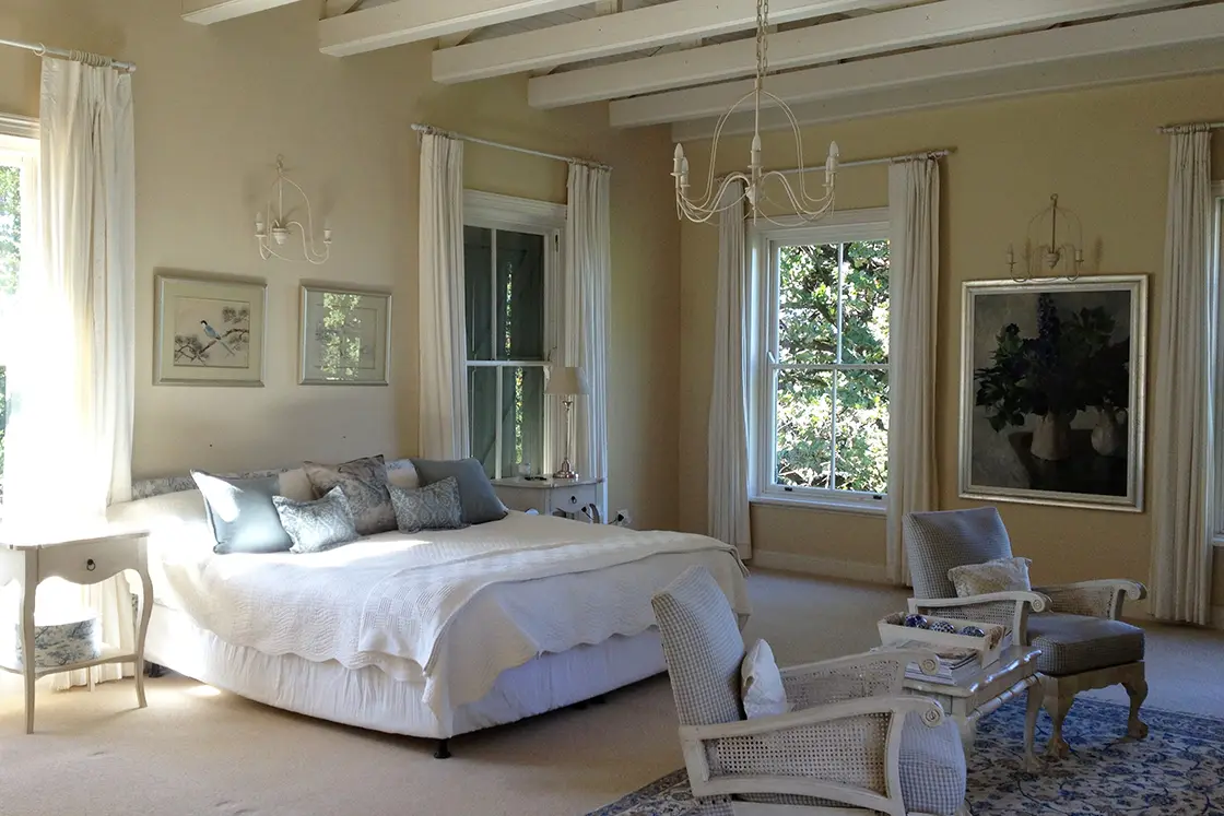 Perfect Hideaways property for sale: A bedroom in the main house, which features cream tones in the walls, bedding, and curtains. Tulbagh Olive Farm, Cape Winelands.