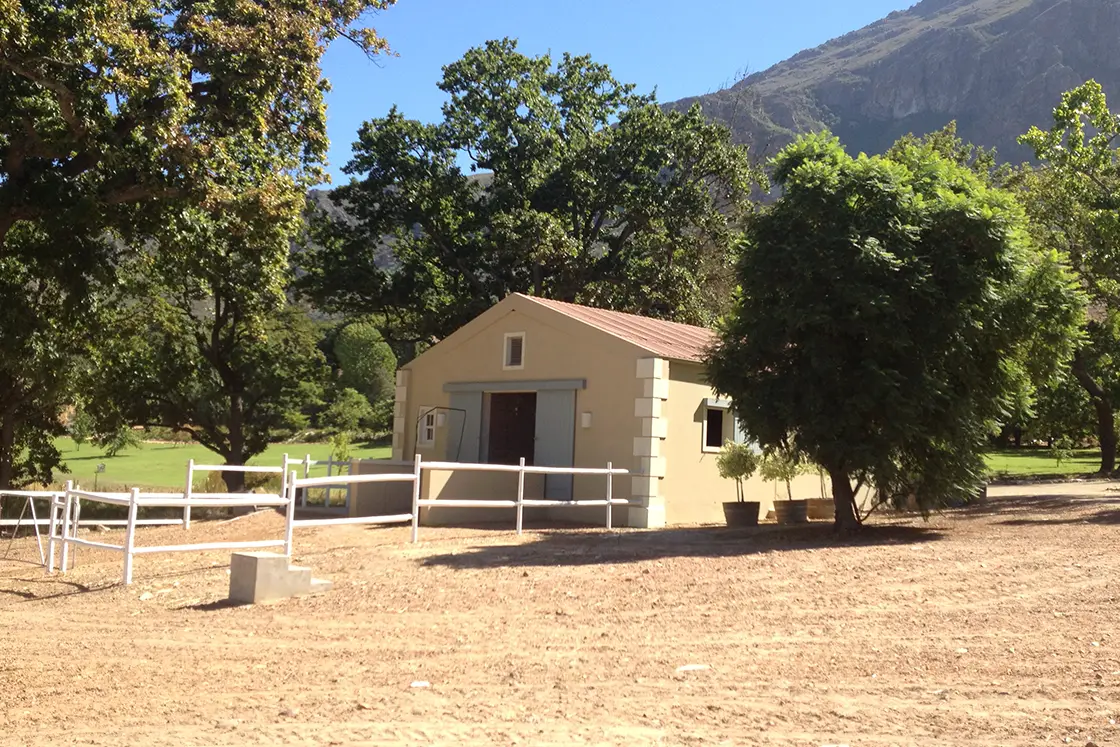 Perfect Hideaways property for sale: A spacious stable with a white fence enclosure, outside the French Provencal-style stable. Tulbagh Olive Farm, Cape Winelands.