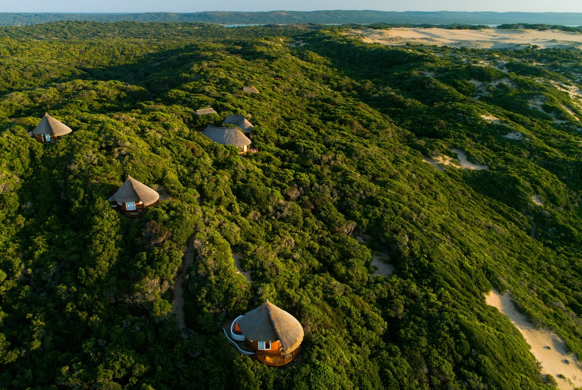 Perfect Hideaways real estate property: Several thatch lodges scattered among the sand banks and trees with a view of the sea in the distance. Dunes de Dovela Lodge, Mozambique.