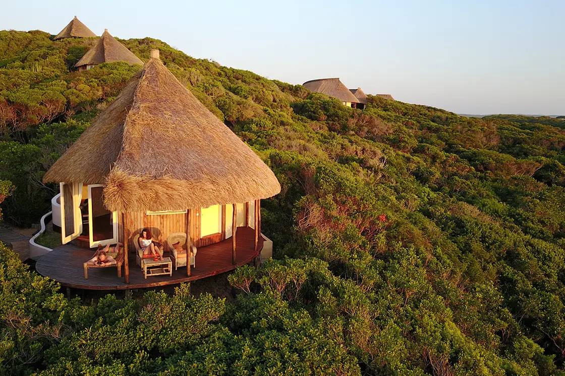 Perfect Hideaways real estate property: A closer image of the guest lodge with people sitting on the balcony chairs and loungers. Dunes de Dovela Lodge, Mozambique.