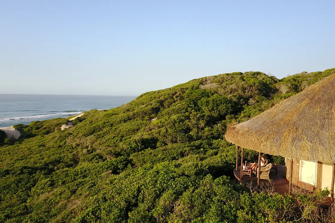 Perfect Hideaways real estate property: A lodge with a sea view and people sitting on the deck. Dunes de Dovela Lodge, Mozambique.