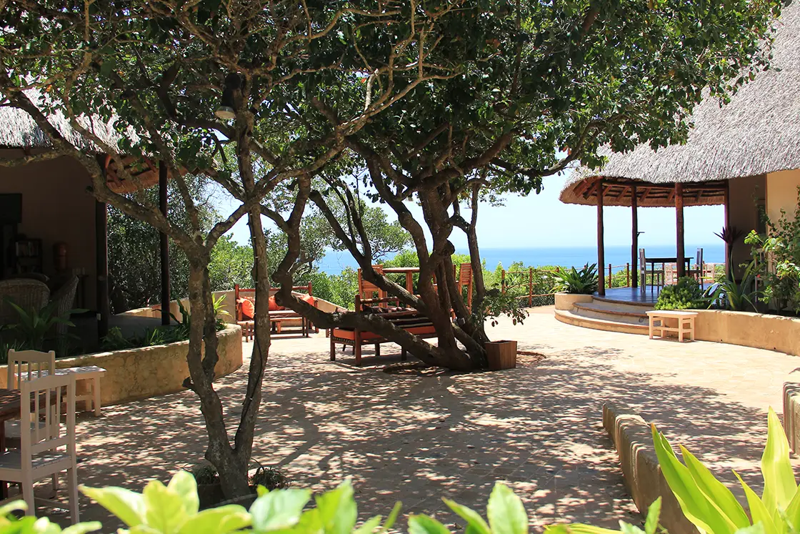 Perfect Hideaways real estate property: The main lodging with the stone courtyard and dining area, with flowers planted along the edges. Dunes de Dovela Lodge, Mozambique.