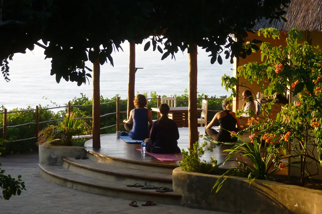 Perfect Hideaways real estate property: People on the main lodge deck doing yoga at sunset with an unobstructed view of the ocean in front. Dunes de Dovela Lodge, Mozambique.