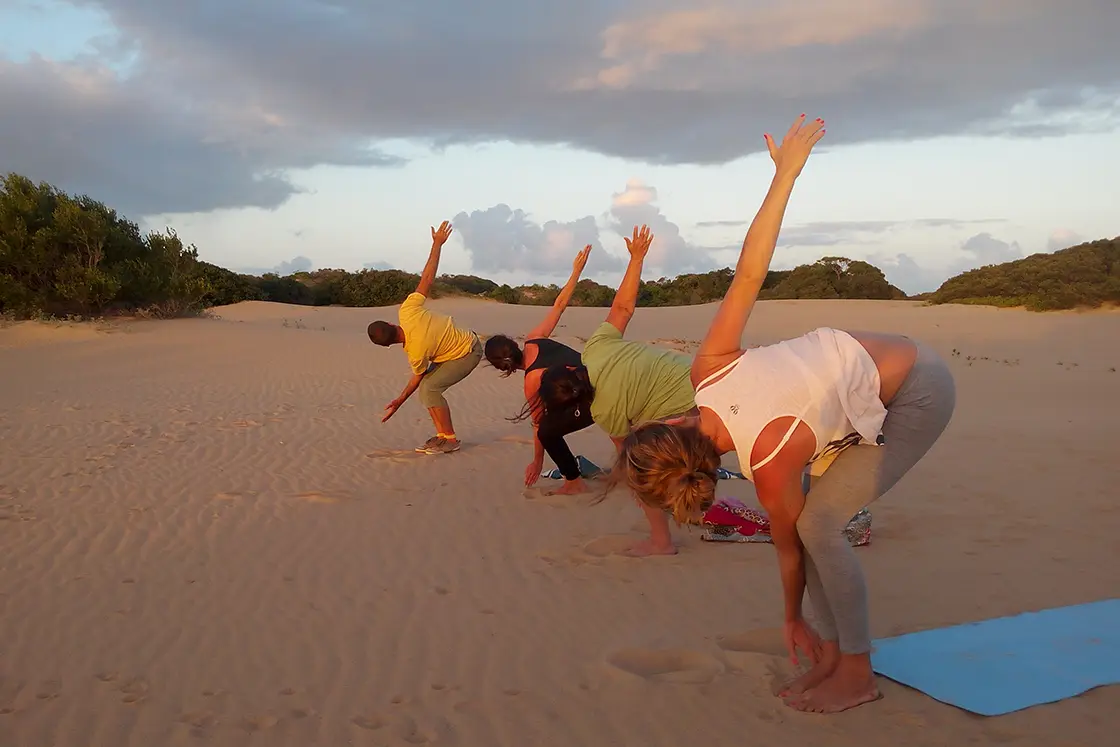 Perfect Hideaways real estate property: People doing yoga on the beach at sunset. Dunes de Dovela Lodge, Mozambique.