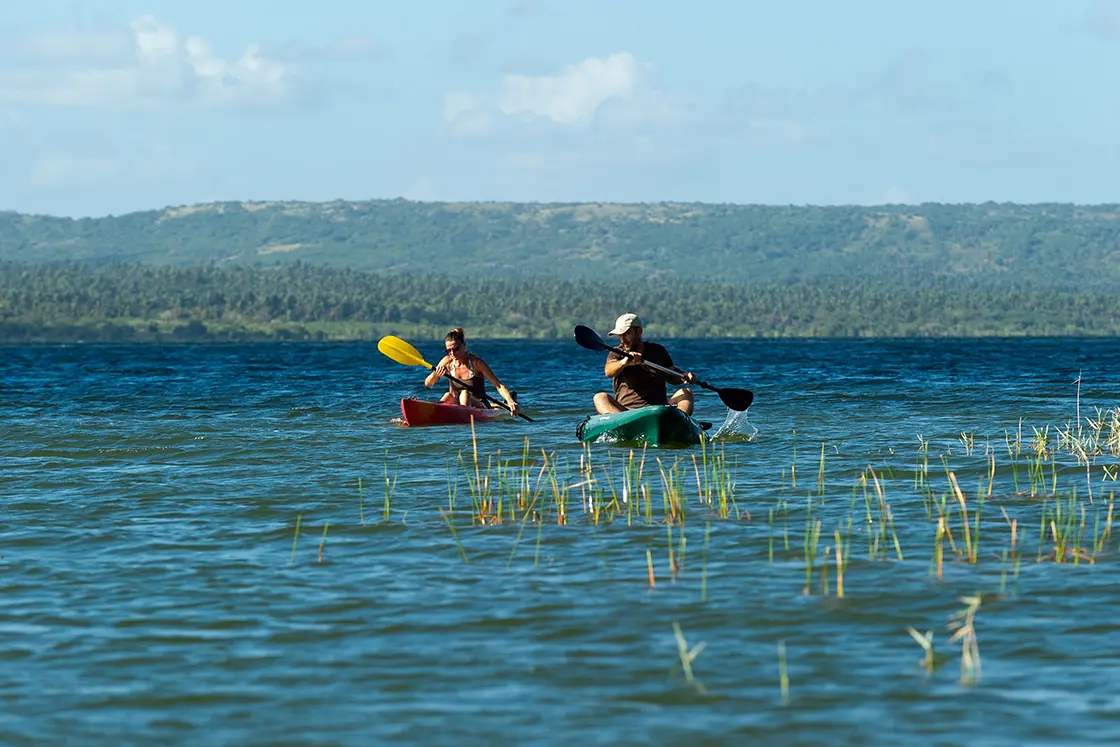 Perfect Hideaways real estate property: People paddling in the kayak on the lagoon with the land in the background. Dunes de Dovela Lodge, Mozambique.