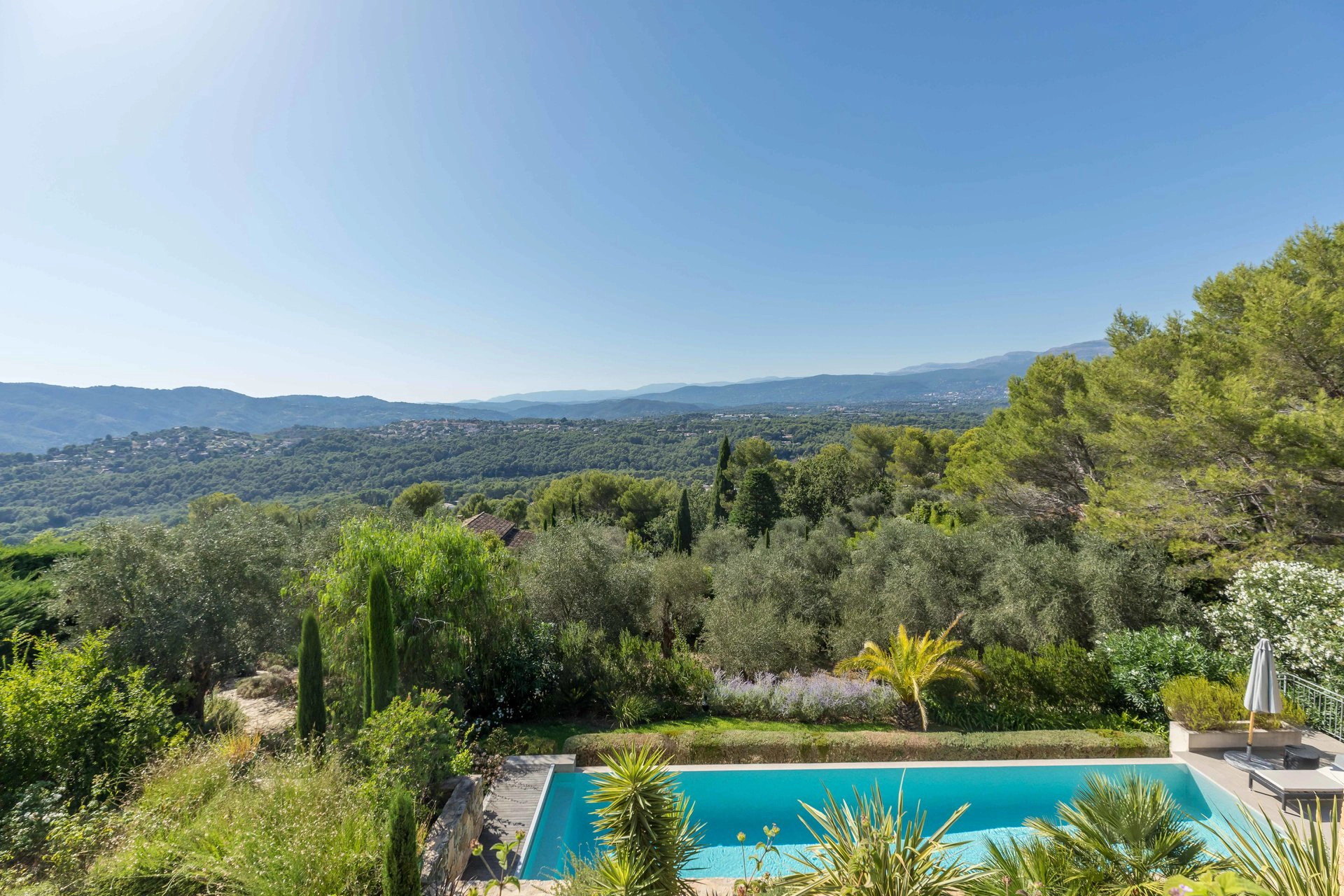 Perfect Hideaways real estate property: A luxurious garden near the pool terrace, which features a sparkling pool and outdoor chairs, and views of the French countryside, located at La Vue in Mougins.