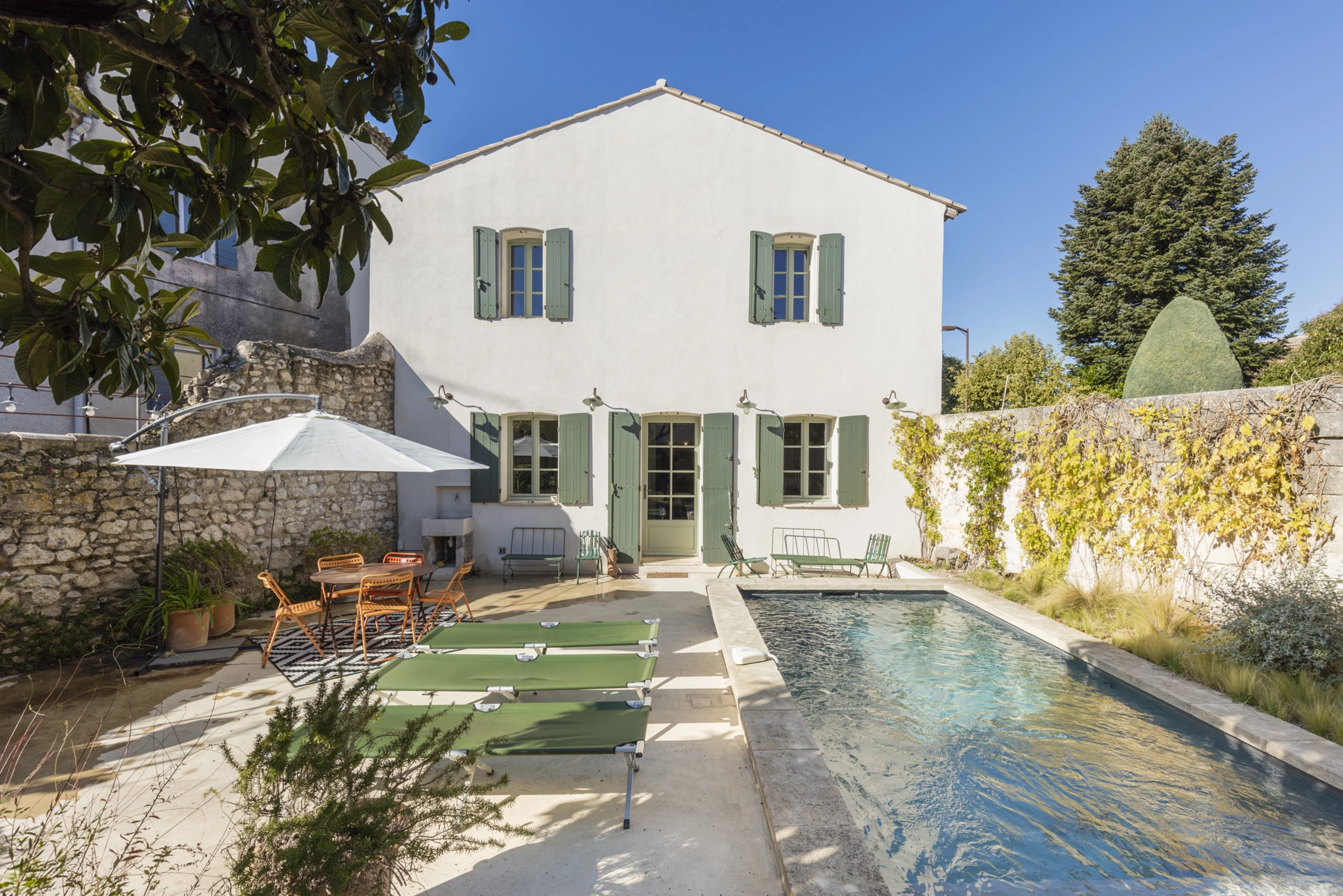 Perfect Hideaways property for sale: The outdoor terrace of a villa, which features a sparkling swimming pool beside an outdoor seating area with comfortable chairs and wall vines surrounding the terrace. France, Villa Sancti.