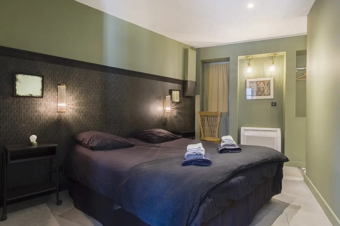 Perfect Hideaways property for sale: A bedroom area, which features a double bed in dark tones, as well as a two-toned wall in dark tones and forest green. France, Villa Sancti.