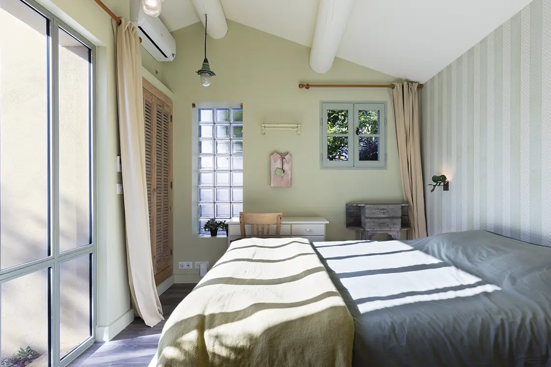 Perfect Hideaways property for sale: A well-lit bedroom area in the villa, which features a double bed and forest tones, visible in the wall colour and linen. France, Villa Sancti.