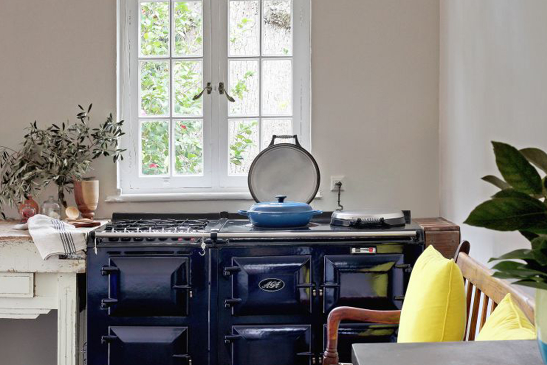 Rustic kitchen decor surrounded by decor contrasting the deep blue of the 6-door Aga stove.