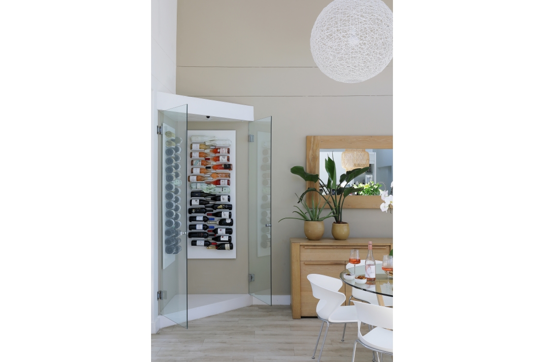 A glass door framed by a wine rack in the modern dining room.