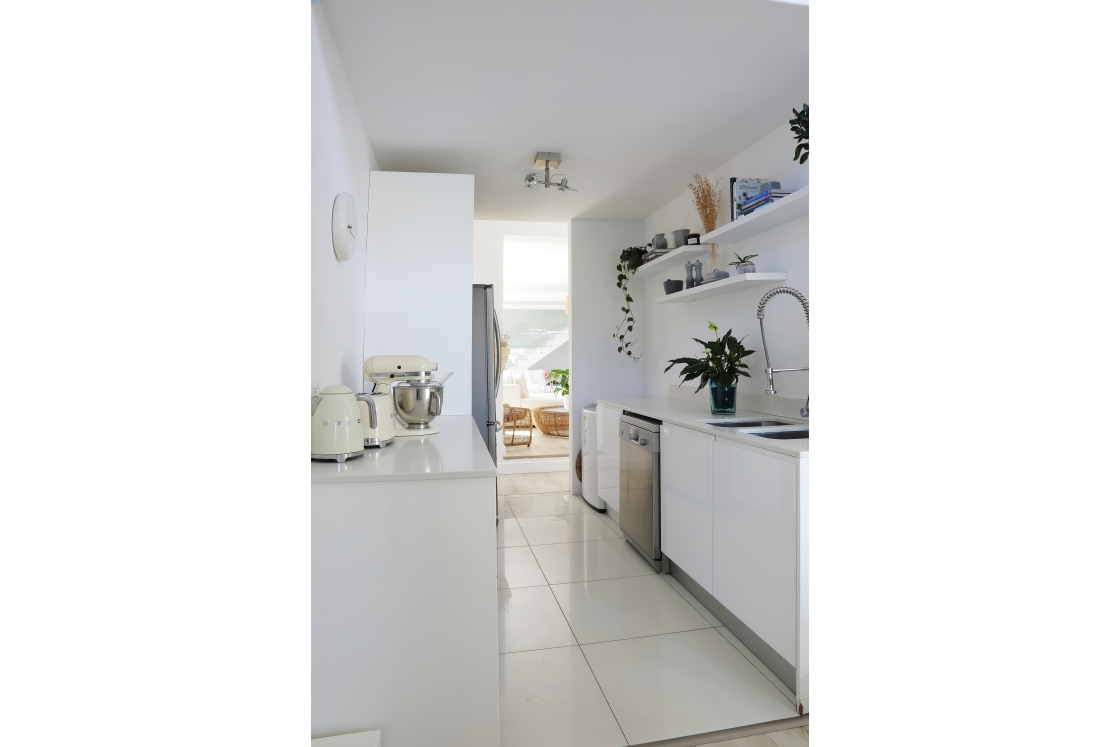 A clean white scullery with a sink, a refrigerator and cooking appliances.