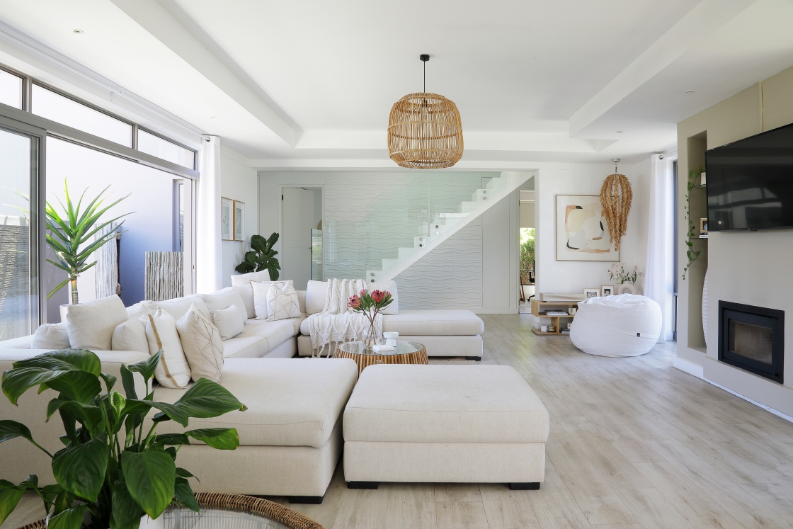 A bright lounge area highlighted by white couch and a cozy fireplace.