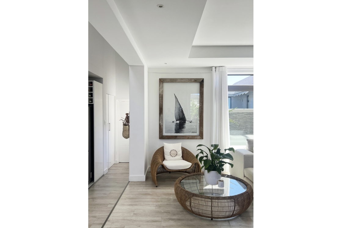 A cozy sitting area featuring a wicker chair and a large picture of a boat on the wall.