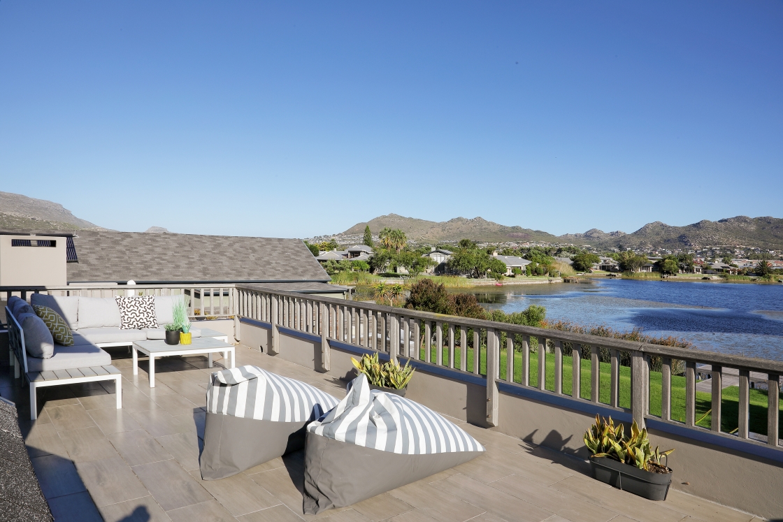 A deck with outdoor furniture, offering a stunning vista of a peaceful lake and surrounding landscape.