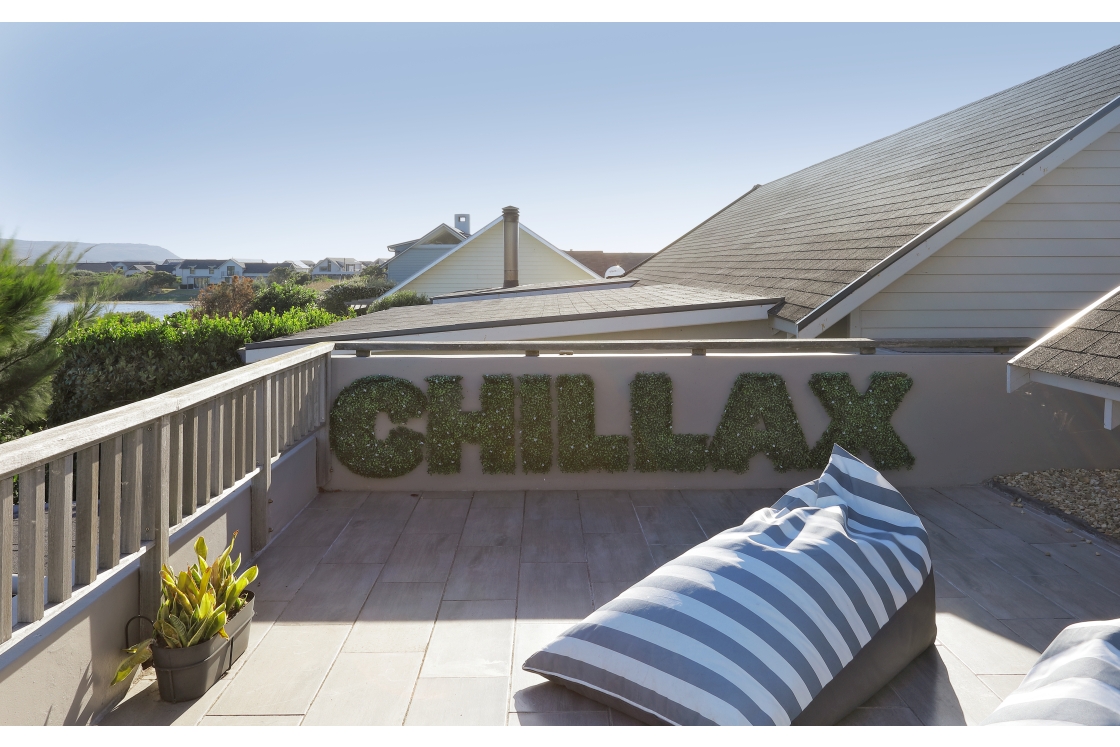 A balcony featuring a prominent sign that reads "Chillax," with loungers.