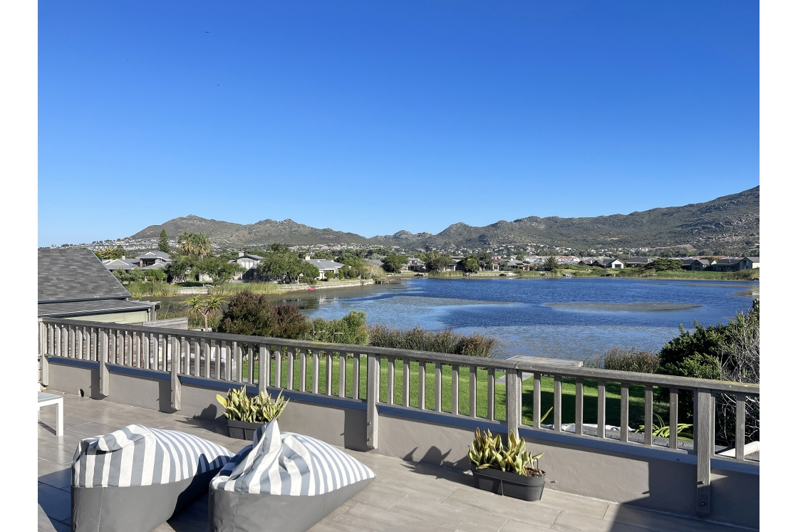 A panoramic view showcasing a lake and mountains, observed from a balcony setting.