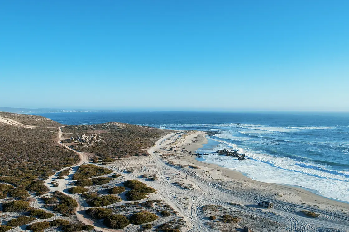 Perfect Hideaways property for sale: A secluded beach surrounded by arid coastal vegetation, with sand trails leading away from the beach, suitable for off road vehicles. Trekoskraal, Paternoster.