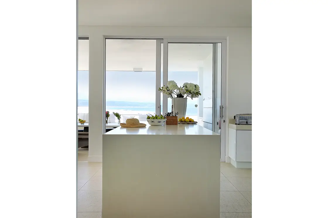 Perfect Hideaways real estate property: The kitchen area of a beach house, featuring primarily white colours for the interior, while brightly coloured decor creates a striking contrast. Roga Rock, Plettenberg Bay.