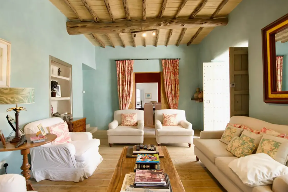 Perfect Hideaways real estate property: A lounge area in the home, which features comfortable seating on wooden floors, a wood ceiling to match the floors, and muted blue tones in the wall colour. Ibiza, Ibizan Finca.