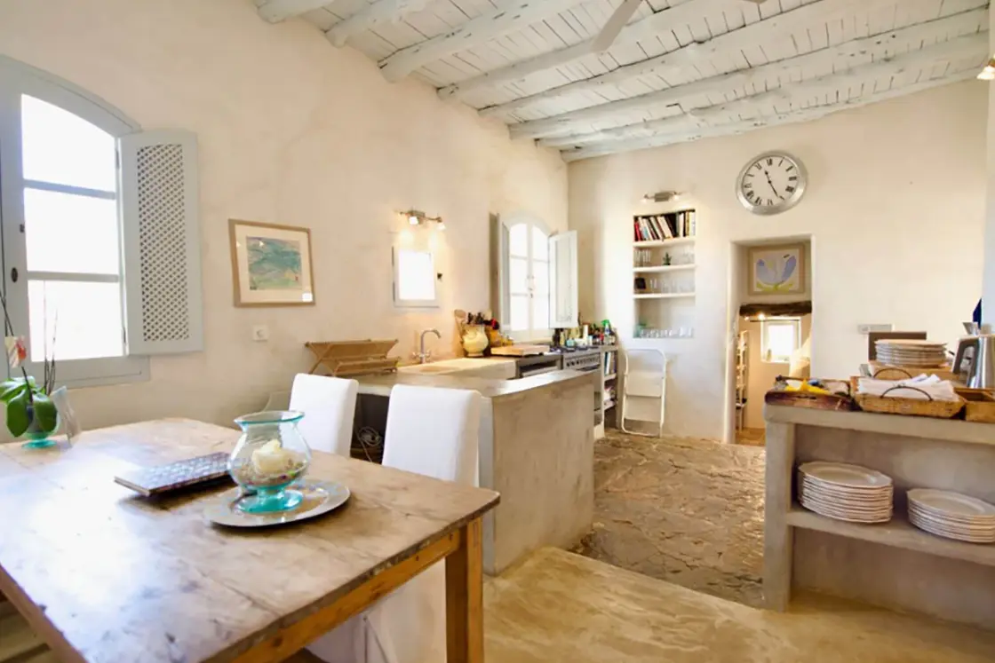 Perfect Hideaways real estate property: A kitchen and dining area within the Spanish-style home, featuring rustic furniture and limewash elements which accentuates the ‘countryside feel’ of the home. Ibiza, Ibizan Finca.