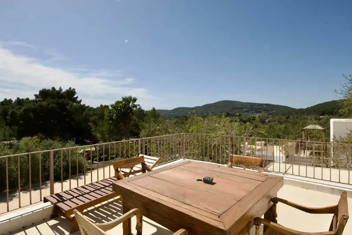 Perfect Hideaways real estate property: An outdoor balcony area with a wooden table and chairs, showcasing the views of the rural countryside from the Spanish, Finca-style home. Ibiza, Ibizan Finca.