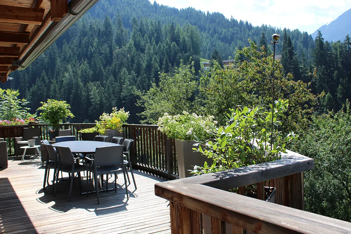 Perfect Hideaways real estate property: An outdoor terrace with a dining table, as well as a comfortable seating area overlooking the valley, which forms part of the Dolomite mountain range. Ragginerhof, Italy.