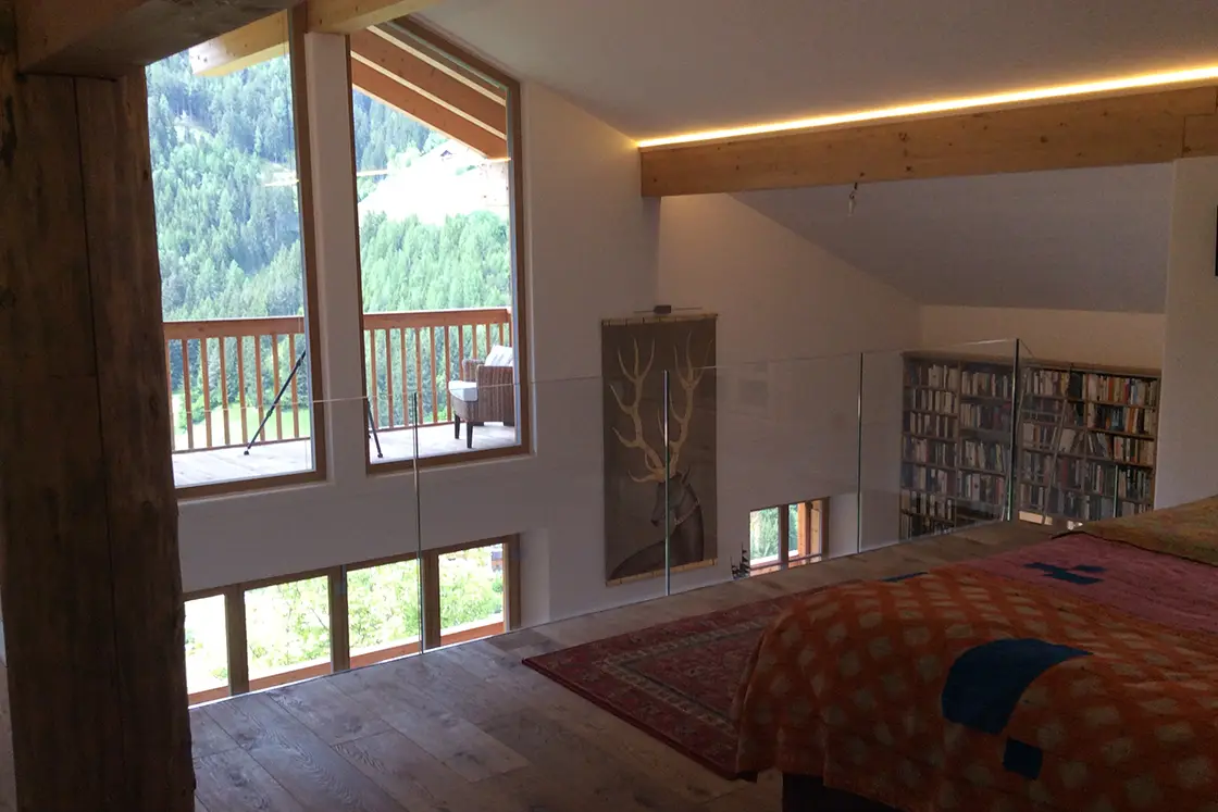 Perfect Hideaways real estate property: The third floor of this Italian countryside chalet, featuring a master suite with an outdoor terrace, and a stairway leading down to a library on the second floor. Ragginerhof, Italy.