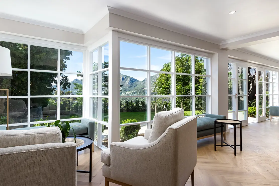 Perfect Hideaways real estate property: A spacious lounge area with a seating area on the left, and French pane windows with views of the garden. The Berg Manor and Villas, Hout Bay.