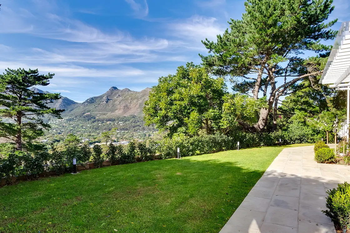 Perfect Hideaways real estate property: A patio on the first floor of a white painted home, featuring large tiles with planting areas in between the tiles, a landscaped garden, and views of Hout Bay. The Berg Manor and Villas, Hout Bay.