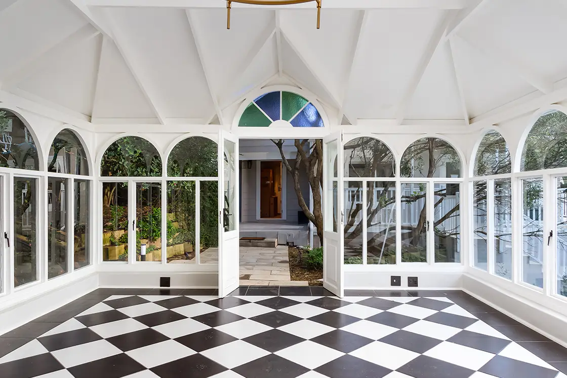 Perfect Hideaways real estate property: A multipurpose conservatory, featuring black-and-white chequerboard tiles, and arched windows. A path leads from the conservatory to the manor house. The Berg Manor and Villas, Hout Bay.