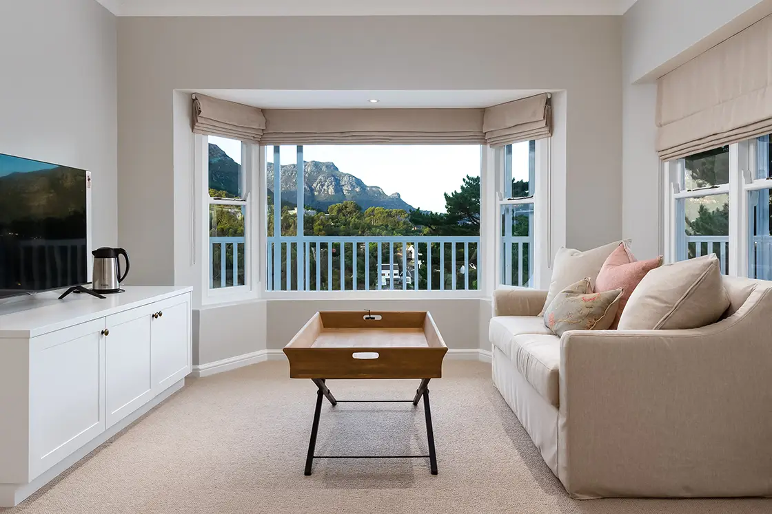 Perfect Hideaways real estate property: A lounge area with an alcove window, featuring a couch facing a cabinet with a tv unit. The Berg Manor and Villas, Hout Bay.