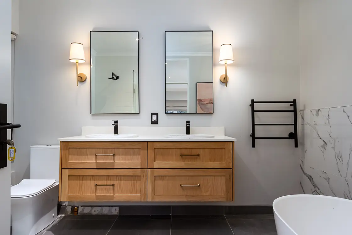 Perfect Hideaways real estate property: A bathroom with a bathtub and toilet, featuring a double basin unit, and side-by-side mirrors with black trim. The Berg Manor and Villas, Hout Bay.