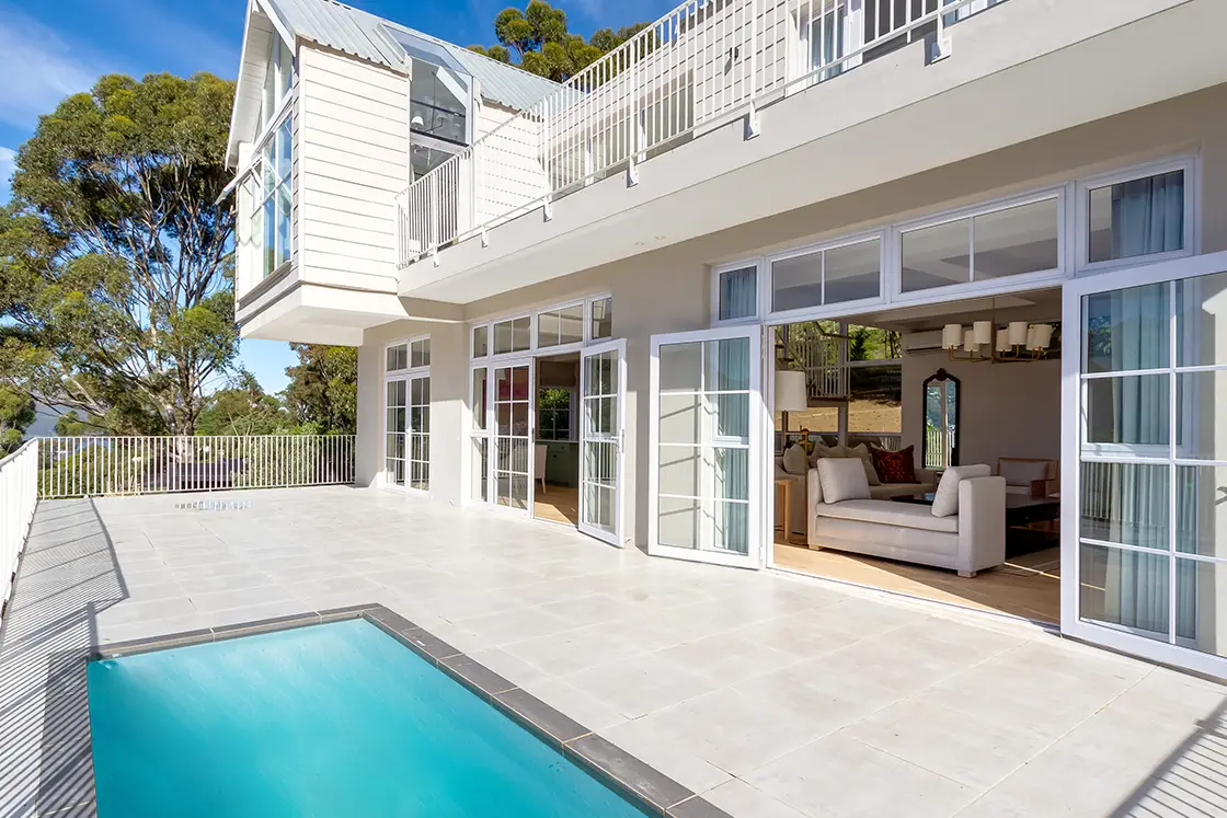 Perfect Hideaways real estate property: The lounge area of the double-story villa, featuring double pane doors, which open onto the patio and pool area. The Berg Manor and Villas, Hout Bay.