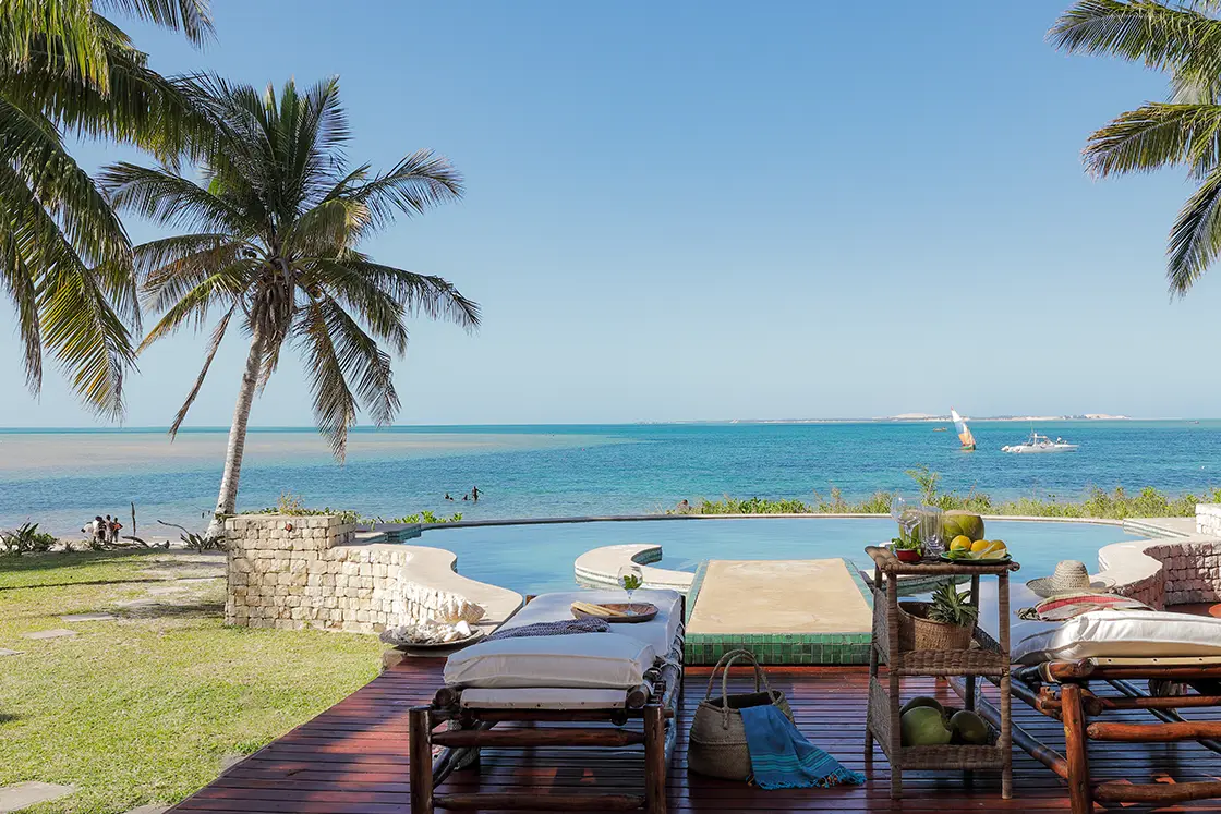 Perfect Hideaways real estate property: A patio area, featuring sun loungers on a wooden deck, a pool, and beach access. Villa Tanga, Benguerra Island.