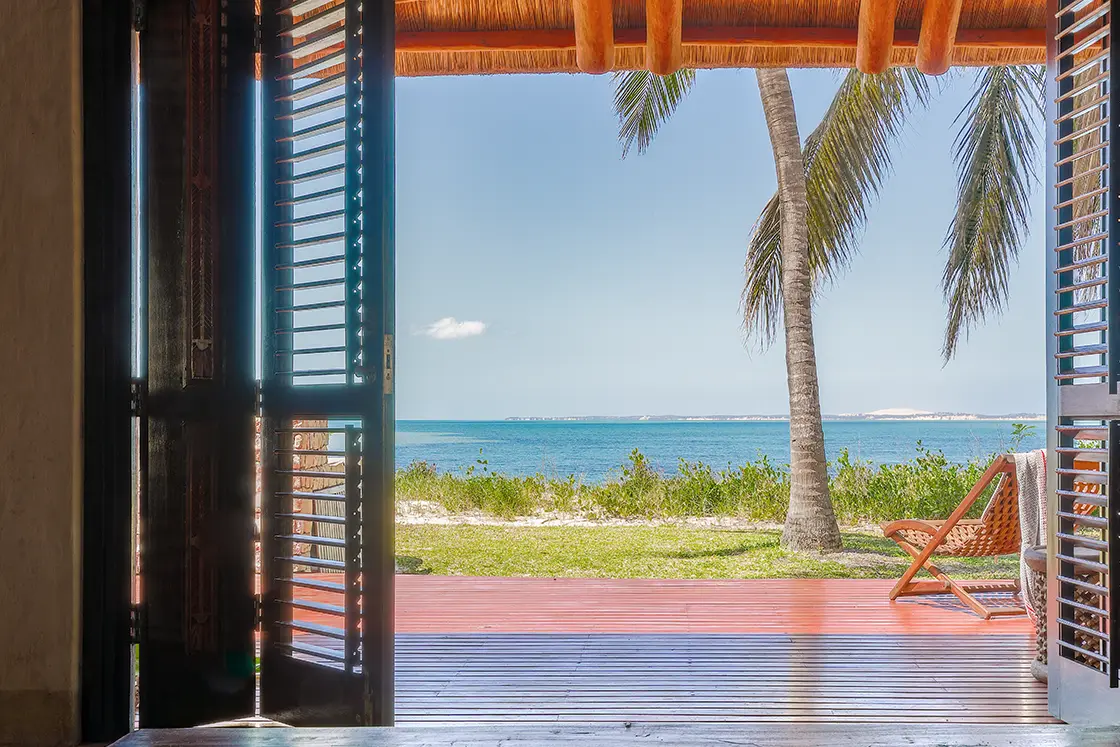 Perfect Hideaways real estate property: A bedroom with open shutter doors, showcasing a patio with beach access and sea views. Villa Tanga, Benguerra Island.