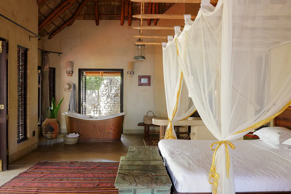 Perfect Hideaways real estate property: A spacious bedroom with an en-suite bathroom, showcasing Mozambican furnishings. Villa Tanga, Benguerra Island.