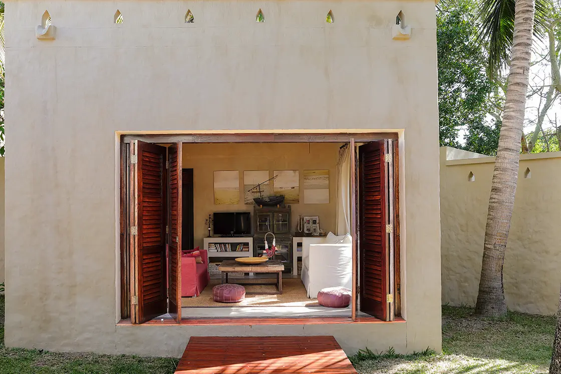 Perfect Hideaways real estate property: A bedroom with a walkway connecting to the villa, featuring wood shutter doors and Mozambican decor. Villa Tanga, Benguerra Island.