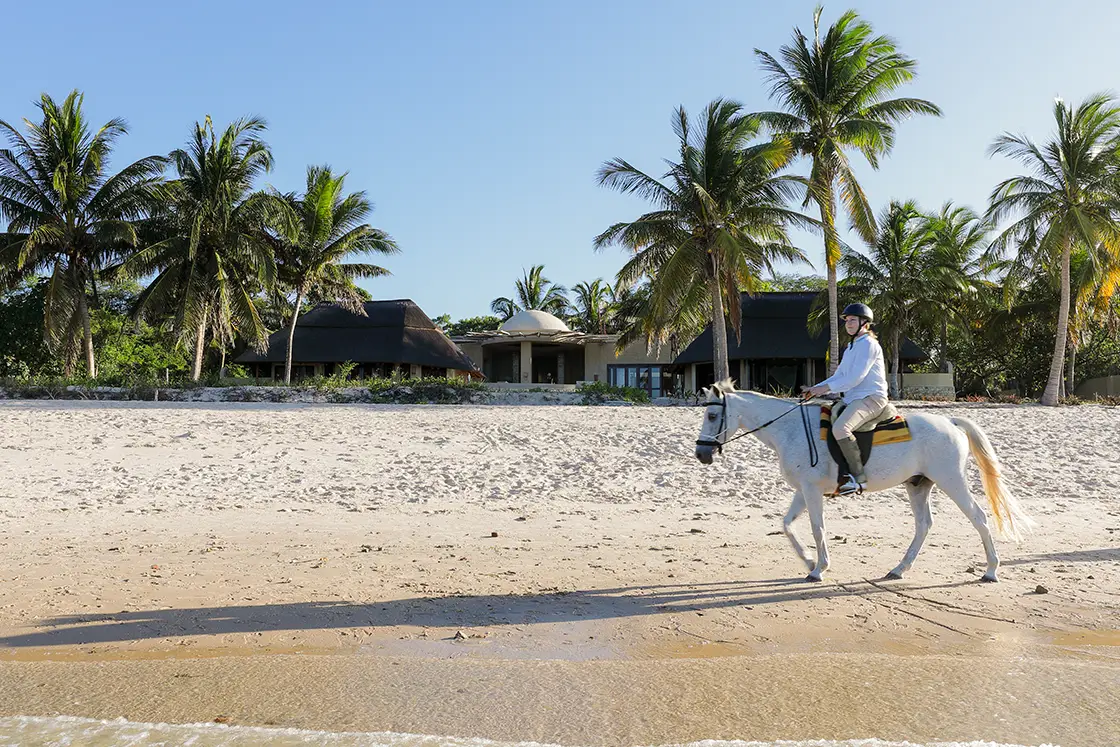 Perfect Hideaways real estate property: A tourist enjoying a horse ride on the beach, showcasing the nearby Moroccan style villa. Villa Tanga, Benguerra Island.