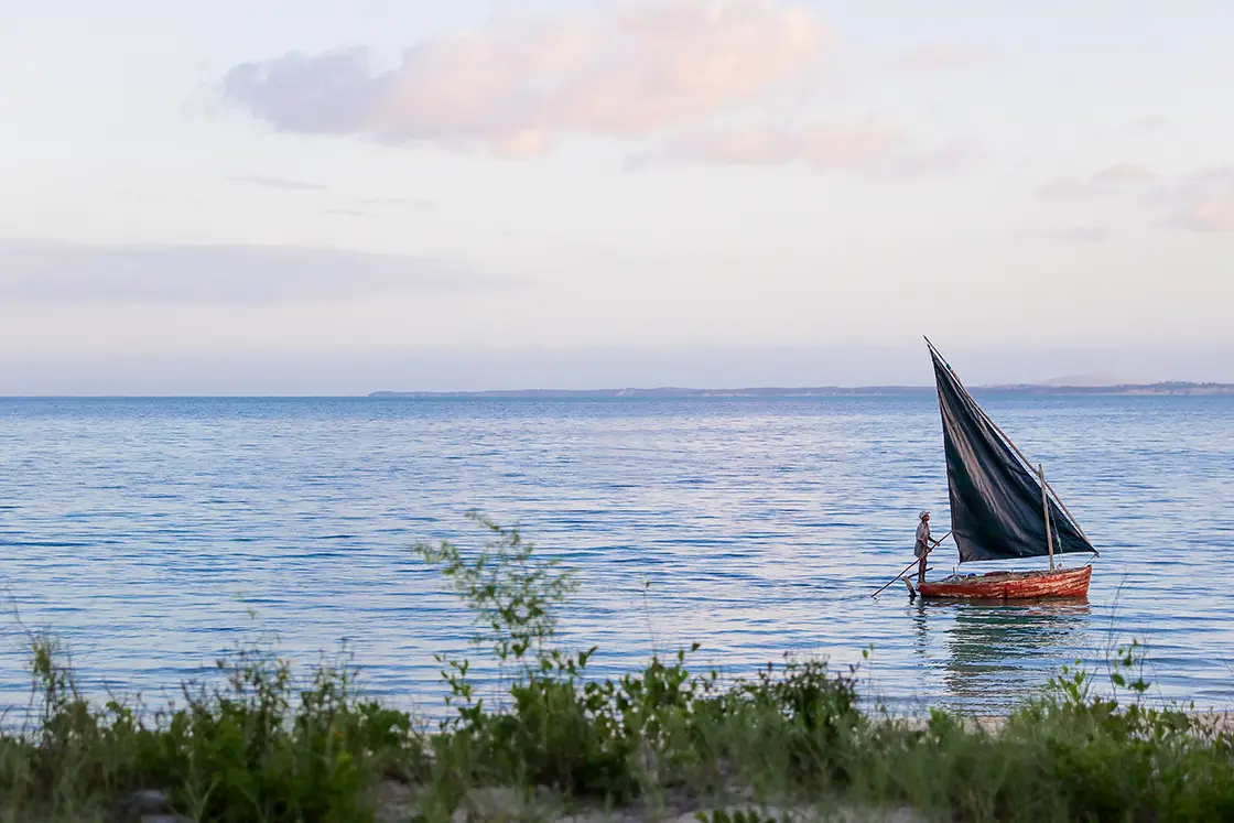 Perfect Hideaways real estate property: A fisherman on a small fishing boat navigates the shallows close to the beach. Villa Tanga, Benguerra Island.