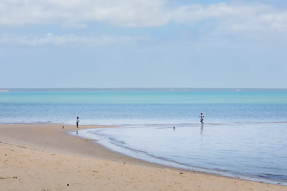 Perfect Hideaways real estate property: People on a beach in Mozambique with open sea views, and an expansive coastline in the background. Villa Tanga, Benguerra Island.