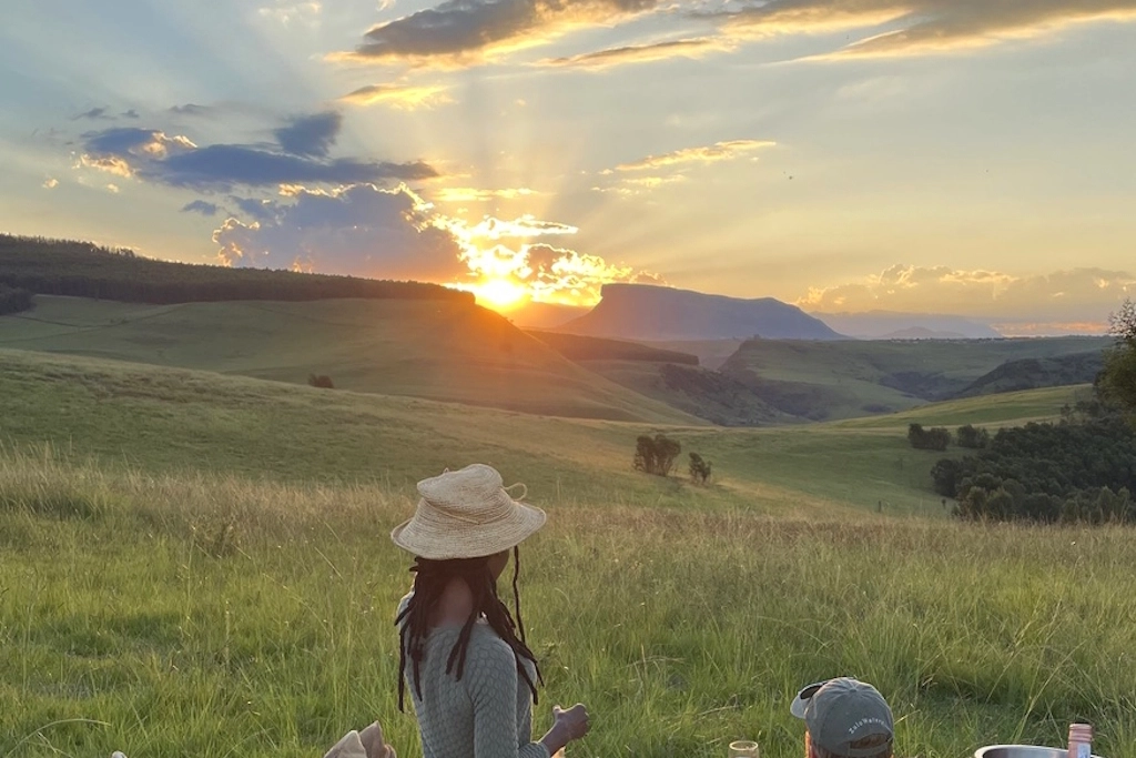 Perfect Hideaways real estate property: Guests having drinks on a grassy hill while the sun sets. Zulu Waters Game Reserve, Natal Midlands.