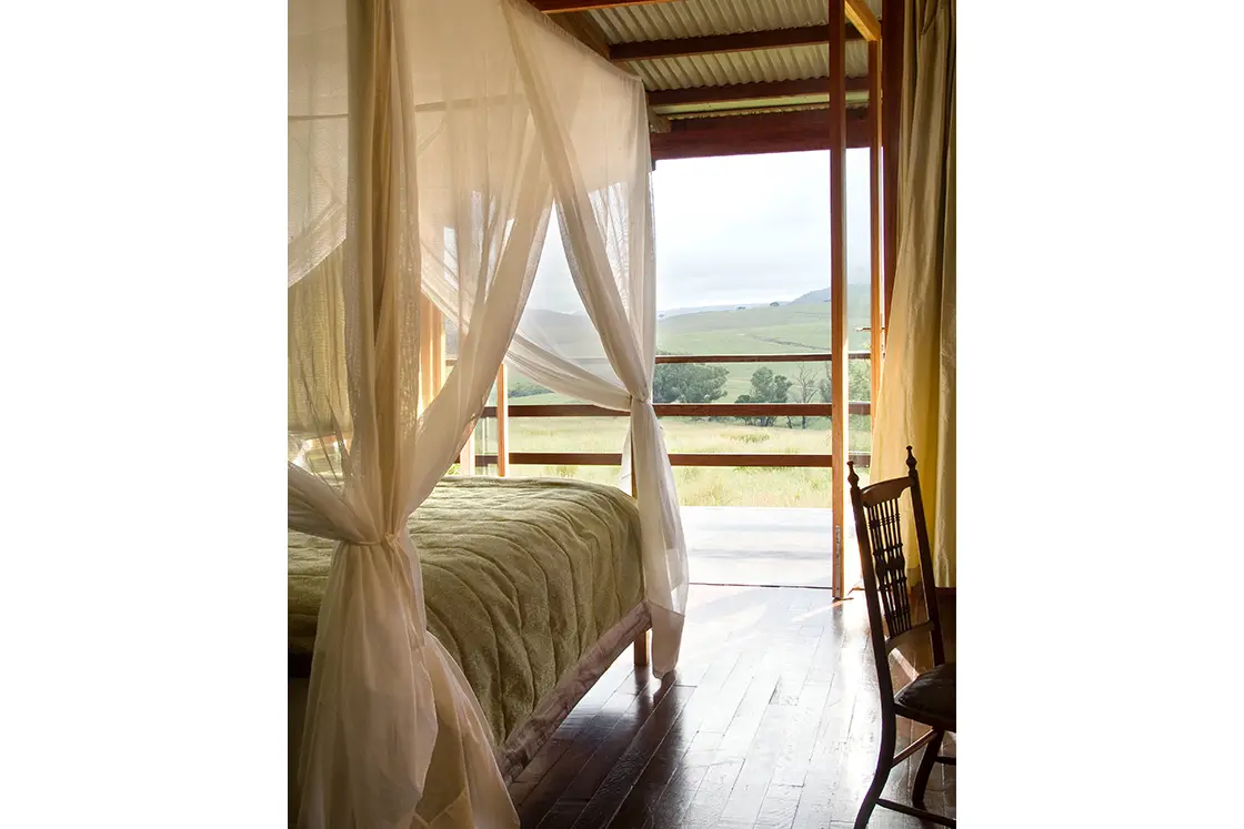 Perfect Hideaways real estate property: A bedroom with a four-poster bed and mosquito nets, as well as a balcony with views of the game reserve. Zulu Waters Game Reserve, Natal Midlands.