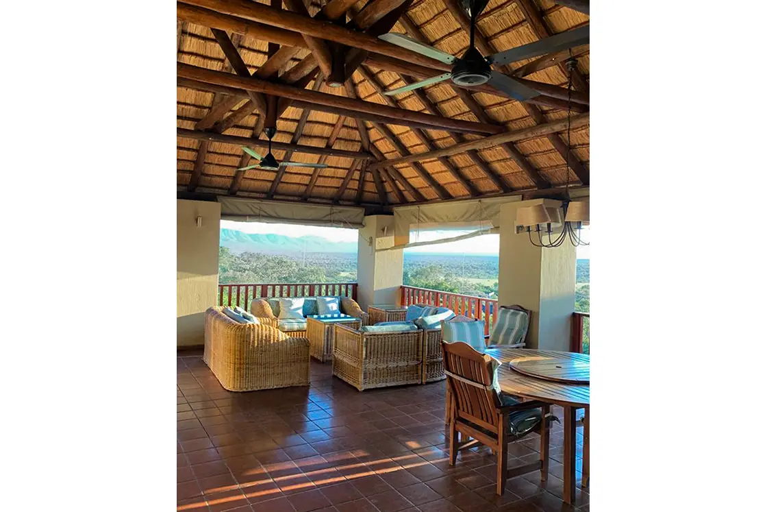 Perfect Hideaways real estate property: The balcony with an outdoor sitting area, dining table, and a view of the reserve terrain in the background and mountain range. Mabula Game Reserve, Limpopo.