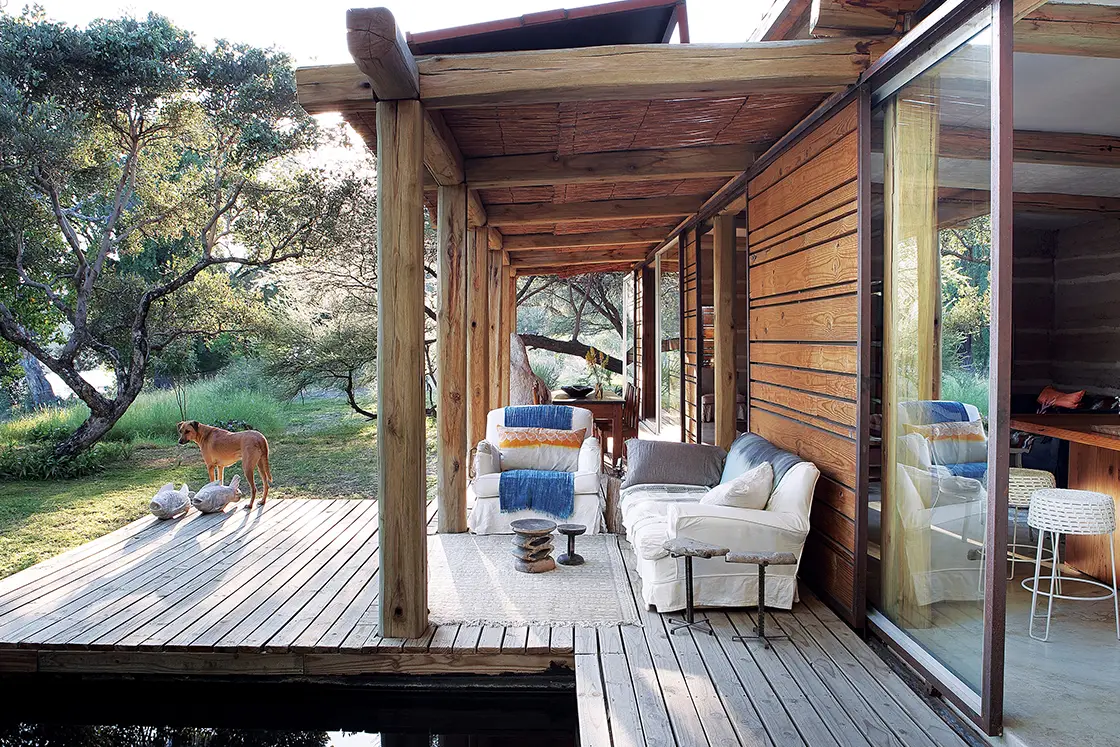 Perfect Hideaways real estate property: An open sliding door from the kitchen area onto the wooden deck, with a pool and comfortable deck seating. Otto House, Okavango Delta.