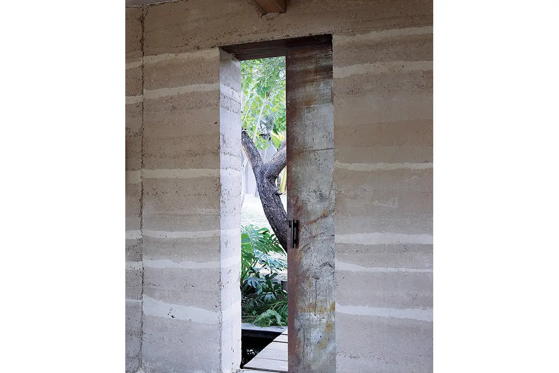 Perfect Hideaways real estate property: A wall in the rammed earth style, and a rustic metal front door. Otto House, Okavango Delta.