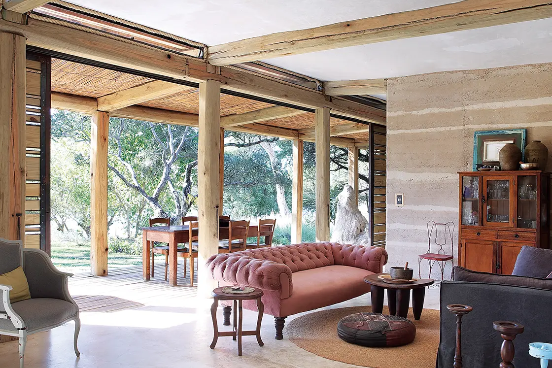 Perfect Hideaways real estate property: A living area, featuring rammed earth, natural wood, and steel architectural elements, and rustic decor. Otto House, Okavango Delta.