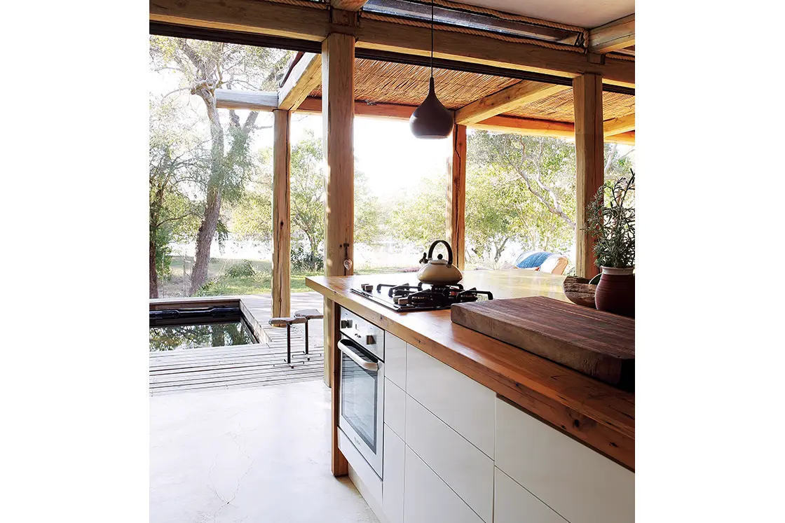 Perfect Hideaways real estate property: An open kitchen, featuring a wood-top kitchen island, and wood deck with a pool. Otto House, Okavango Delta.